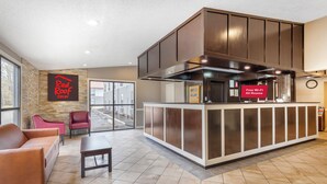 Een Red Roof Inn lobby met een receptiebalie, een zithoek en uitzicht naar buiten.