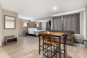 A hotel room with a bed, a desk with chairs, a sofa, a TV, and a window with curtains. - Red Roof Inn & Suites Newport News (Newport News)