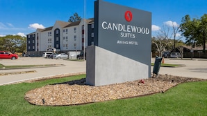 A sign for Candlewood Suites, an IHG hotel, with a modern building in the background.