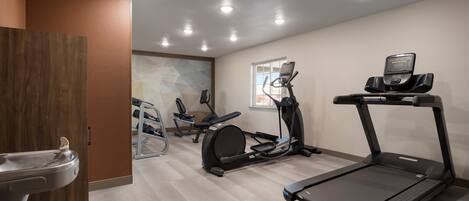 Un gimnasio con cinta de correr, elíptica y bicicleta estática.