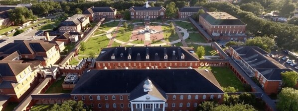 Vista aérea de un campus con varios edificios, un patio central con una fuente y un gran edificio con una cúpula al frente.