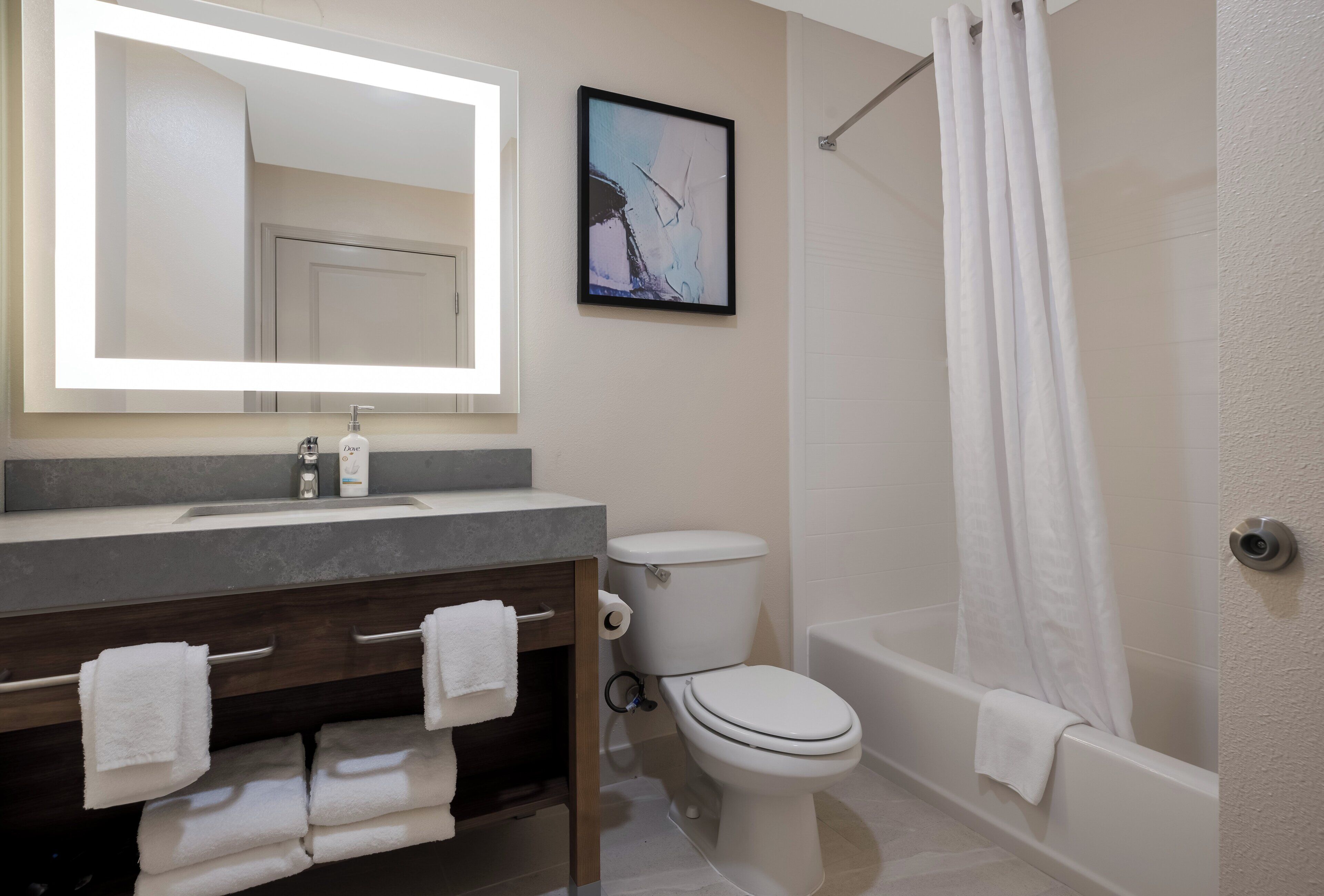 Un baño con inodoro, lavamanos con espejo y bañera.