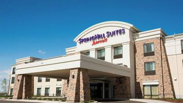 Un hotel con fachada de piedra, un acceso cubierto y un cartel que dice "Springhill Suites Marriott".