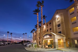 A hotel with a modern facade, palm trees, and a parking lot. - Candlewood Suites Yuma by IHG (Yuma)