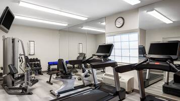 A gym with treadmills, weight machines, and a mirrored wall.