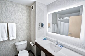 Un bagno con un WC bianco, un lavabo con uno specchio e due asciugamani su un portasciugamani.