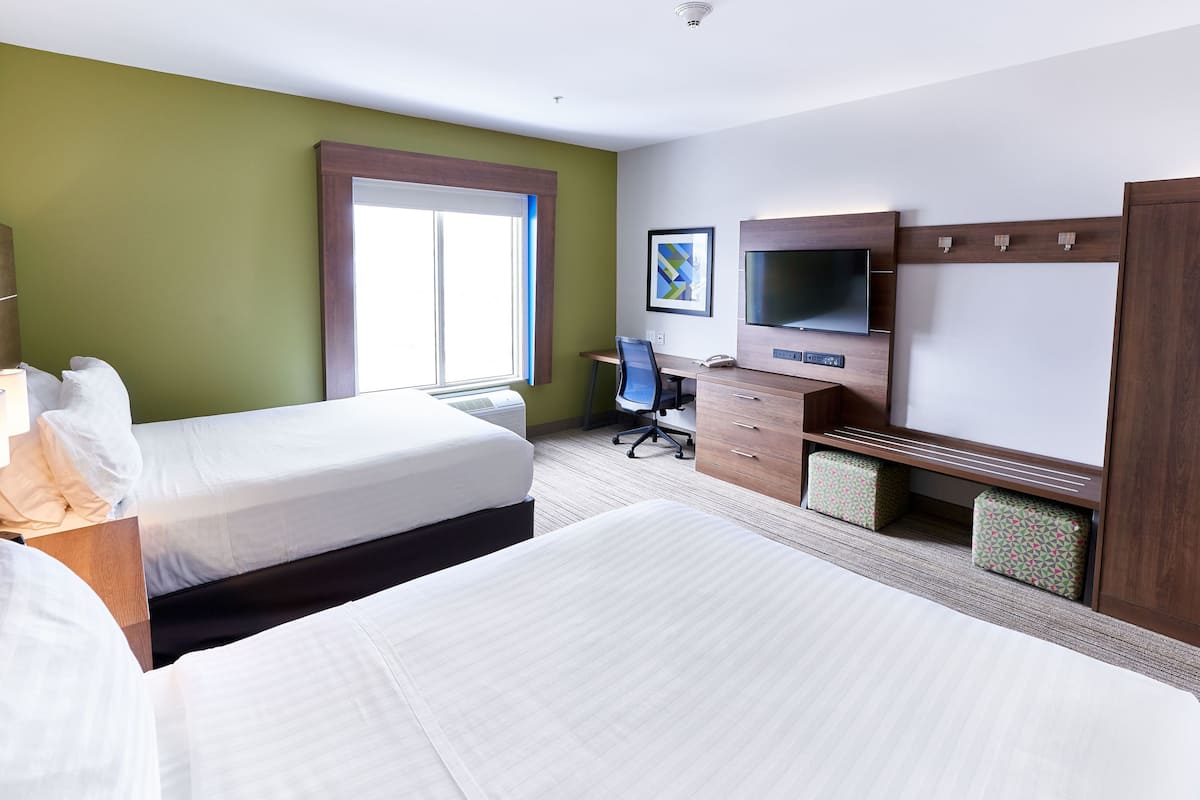 Hotellihuone, jossa on kaksi sänkyä, työpöytä, tuoli, televisio ja ikkuna.