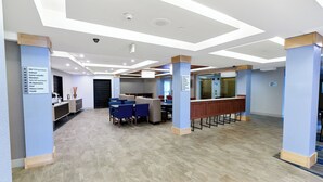 Un vestíbulo de hotel con mostrador de recepción, zona de estar y señalización.