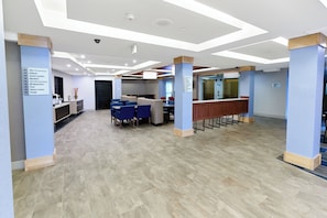 Un vestíbulo de hotel con mostrador de recepción, zona de estar y señalización.