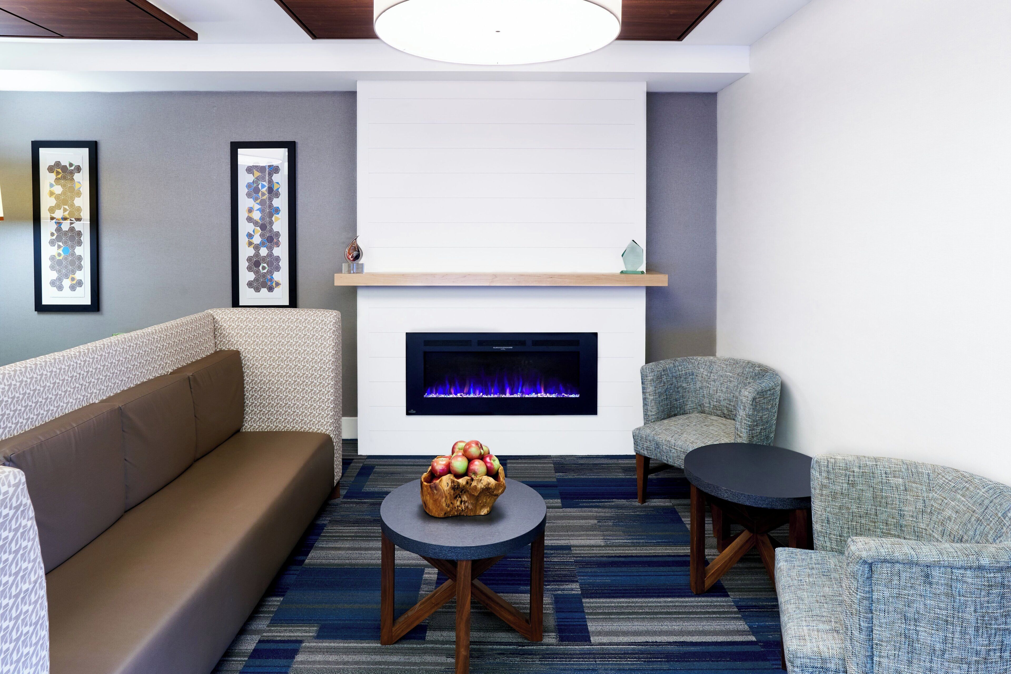 Una sala de estar moderna con chimenea, un sofá, dos sillones y una mesa de centro con un frutero.