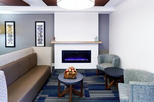 Una sala de estar moderna con chimenea, un sofá, dos sillones y una mesa de centro con un frutero.