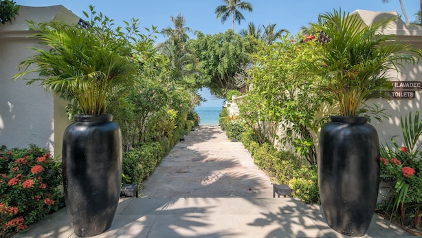 A pathway leading to a beach with palm trees and a sign indicating lavatory facilities. - The Sunset Beach Resort & Spa Taling Ngam (Koh Samui)