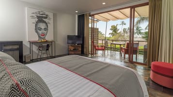 A hotel room with a large bed, a TV, a desk with a chair, and a balcony with outdoor seating.