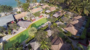An aerial view of a resort with multiple bungalow-style buildings, a central swimming pool, and a beach in the background. - The Sunset Beach Resort & Spa Taling Ngam (Koh Samui)