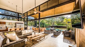 A spacious living area with a modern kitchen, a large dining set, and a view of a swimming pool. - Reserva Conchal Beach Resort, Golf & Spa (Cabo Velas)