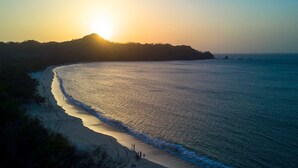 A beach with a curved shoreline, a small group of people, and a distant landmass. - Reserva Conchal Beach Resort, Golf & Spa (Cabo Velas)