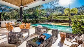 An outdoor pool area with wicker furniture and a ceiling fan. - Reserva Conchal Beach Resort, Golf & Spa (Cabo Velas)