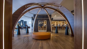 Un interior moderno con una zona de estar central, un bar y un restaurante llamado "360º".