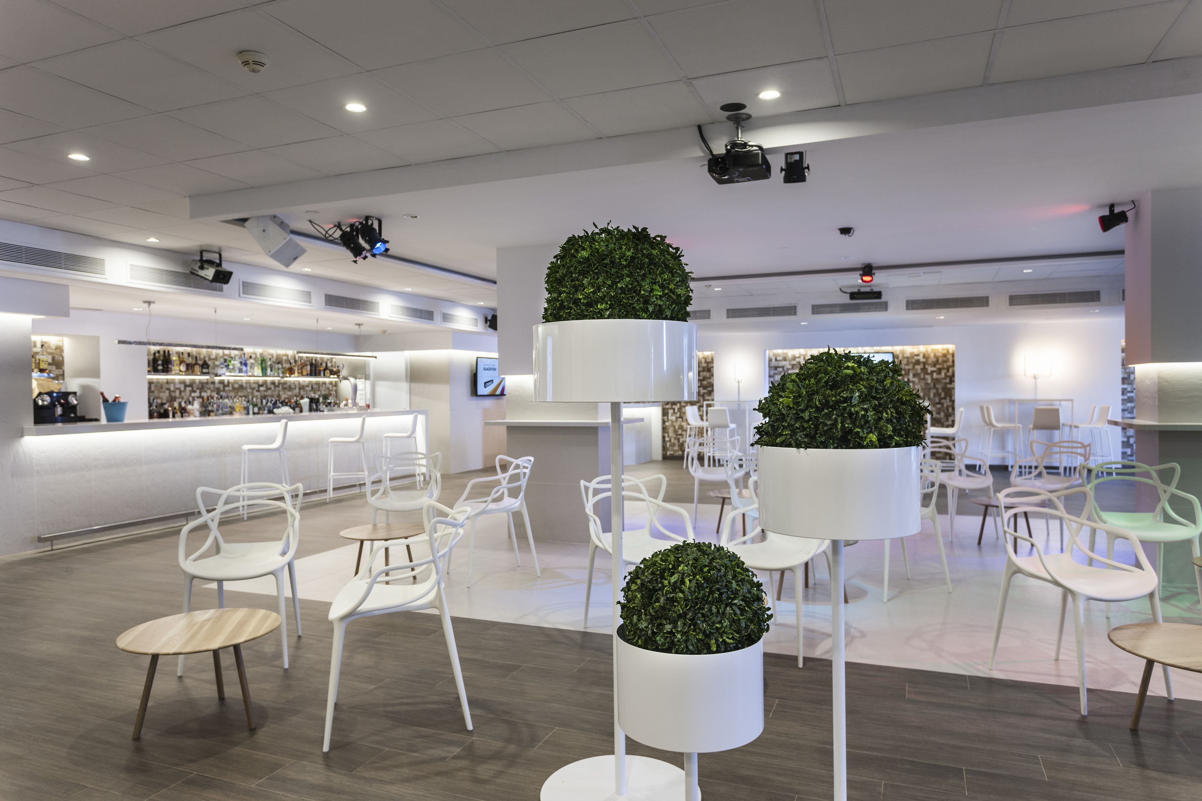 A modern interior with white furniture, a reception area, and potted plants.
