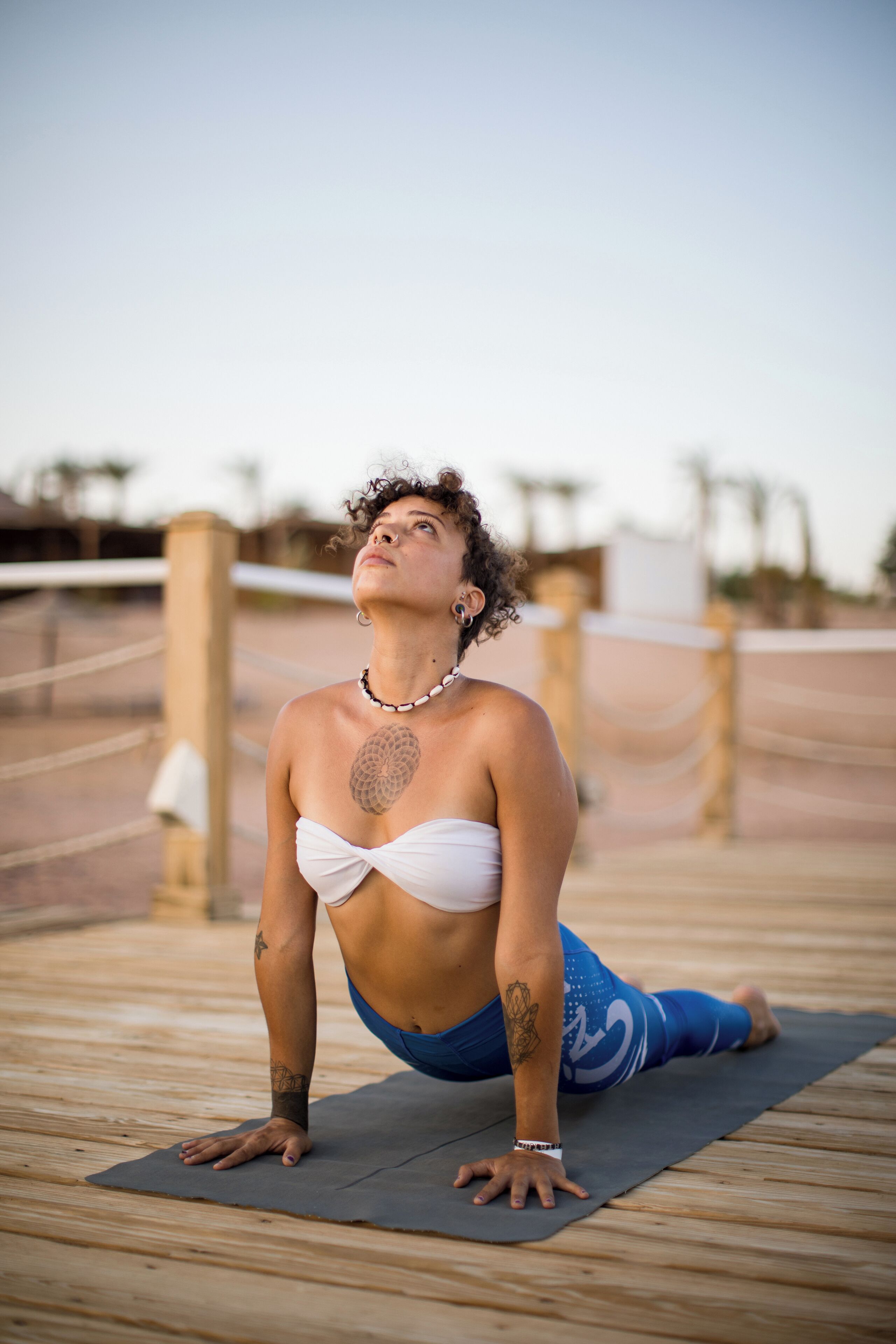 A person performing a yoga pose on a wooden deck with a clear sky in the background.