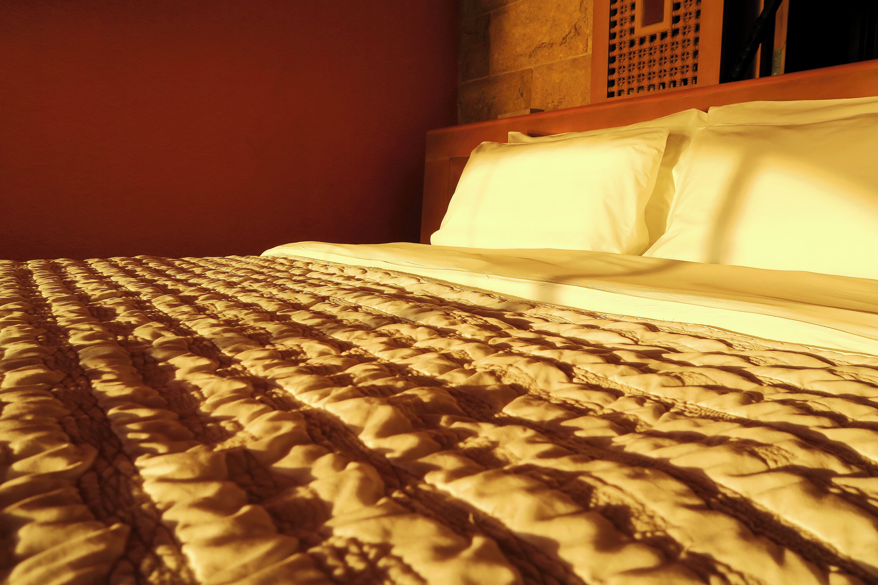 A bed with a textured blanket and white pillows.