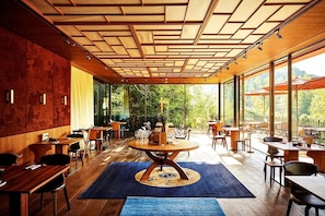 A modern restaurant with a wooden ceiling, large windows, and a central round table. - Schloss Elmau Luxury Spa Retreat & Cultural Hideaway (Kruen)