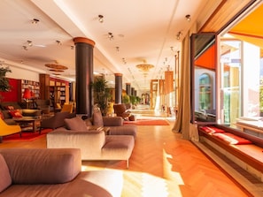 Eine großzügige Lobby mit einer zentralen Sitzecke, großen Fenstern und einem modernen Design.