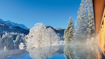 Una vista despejada de un paisaje montañoso con árboles nevados y un estanque que refleja el entorno.