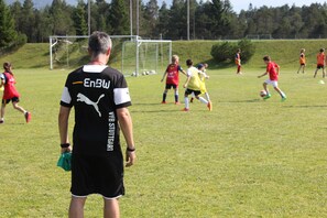 A soccer field with players in red and yellow jerseys. - Schloss Elmau Luxury Spa Retreat & Cultural Hideaway (Kruen)