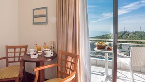 Un balcón con una mesa dispuesta para el desayuno, sillas y vistas al mar.