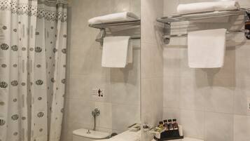 Une salle de bain avec deux lavabos, un rideau de douche, un porte-serviettes et des toilettes.