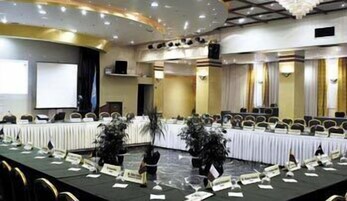 Un salón de conferencias con una larga mesa, tarjetas de identificación y sillas dispuestas para una reunión.
