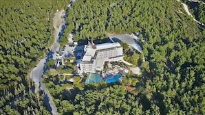 Vista aérea de un resort con un edificio grande, piscina y bosque circundante.