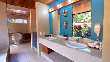 A modern bathroom with two sinks, a large mirror, and a ceiling with wooden panels.