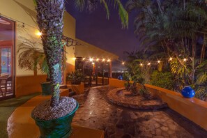 A nighttime outdoor area with a stone pathway, potted plants, and string lights. - Xandari Resort And Spa (San Isidro)
