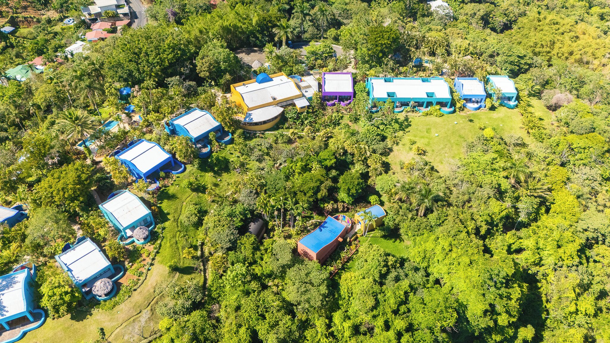 An aerial view of a resort with multiple buildings surrounded by dense greenery.
