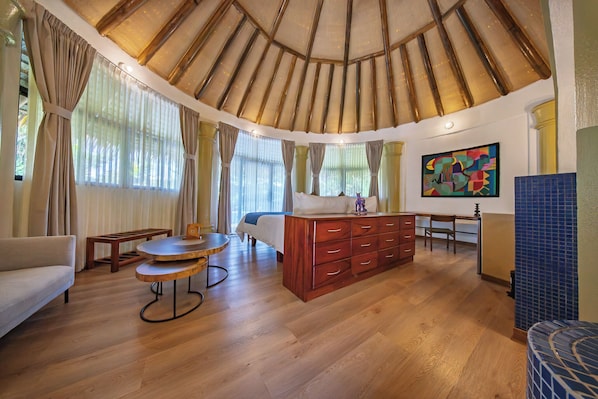 A room with a wooden ceiling, a bed, a wooden dresser, a round table, and a painting on the wall. - Xandari Resort And Spa (San Isidro)