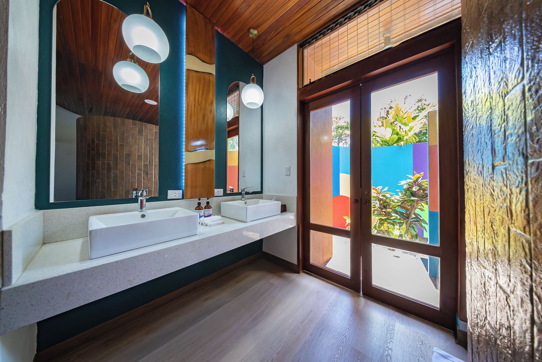Een moderne badkamer met twee wasbakken, een grote spiegel en een houten plafond.