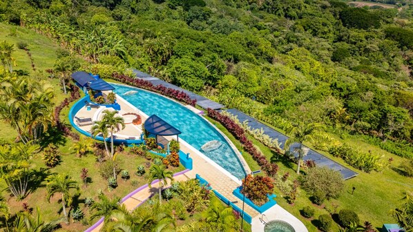 A resort with a large swimming pool, sun loungers, and a lush green landscape. - Xandari Resort And Spa (San Isidro)