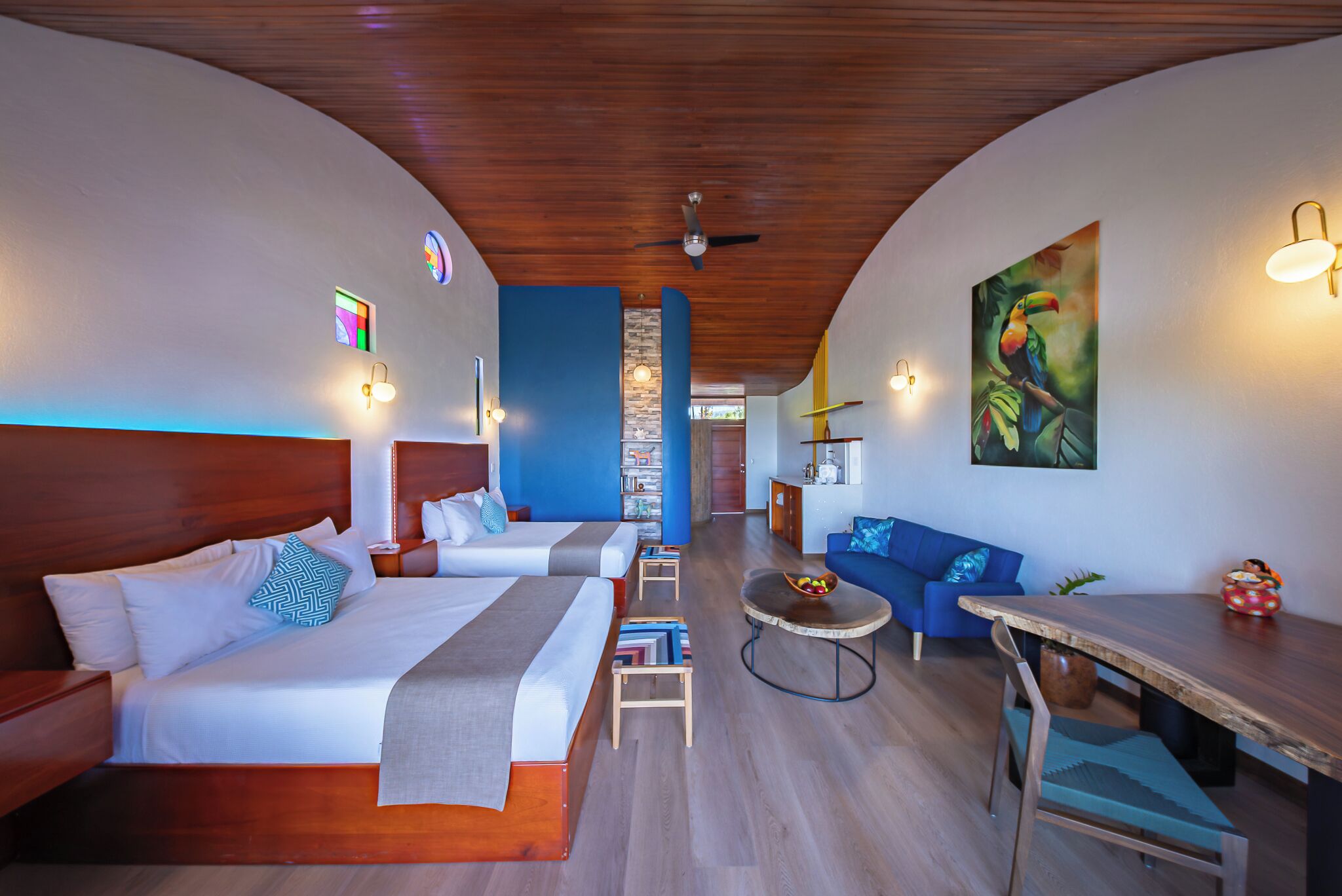 Une chambre d’hôtel avec un plafond en bois, deux lits, une table à manger et un canapé.