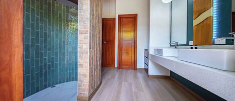 A modern bathroom with a stone wall, wooden door, and a large mirror.