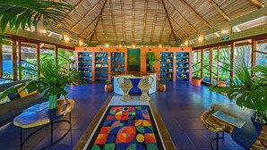 A reception area with a thatched roof, a reception desk, seating, and potted plants. - Xandari Resort And Spa (San Isidro)