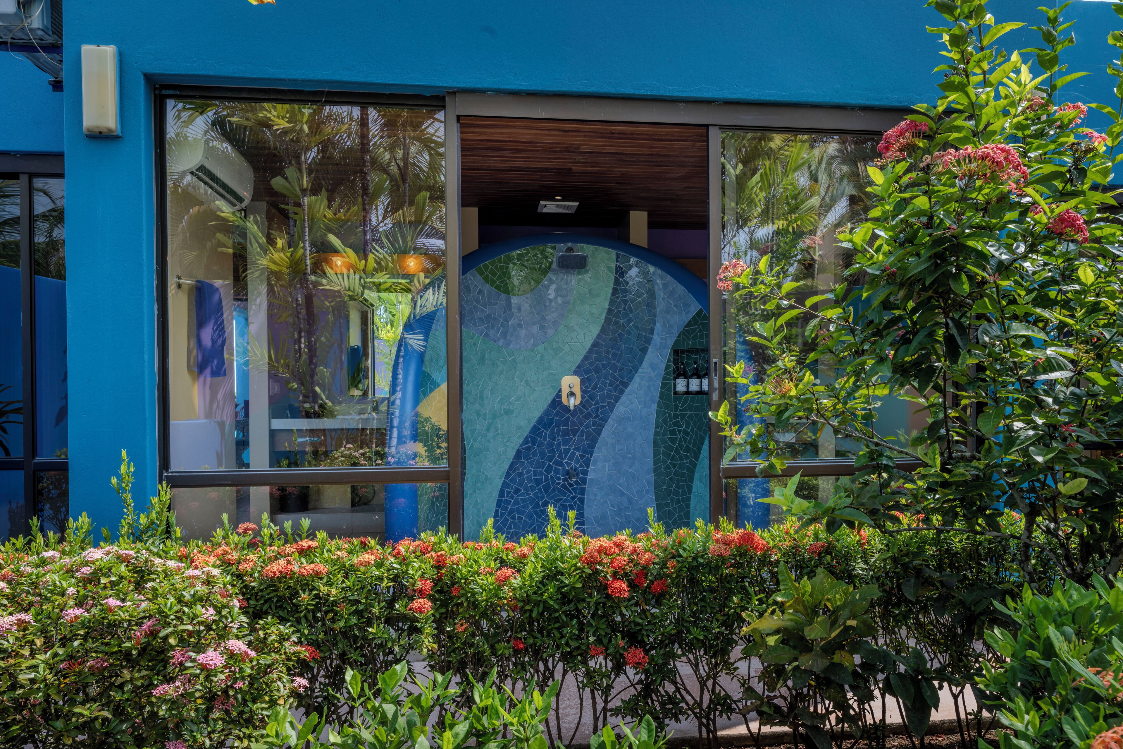 A building with a blue exterior, large glass windows, and a mosaic design on the wall.