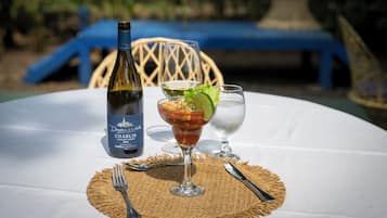 A table with a bottle of wine, a cocktail glass, and a water glass on a white tablecloth.