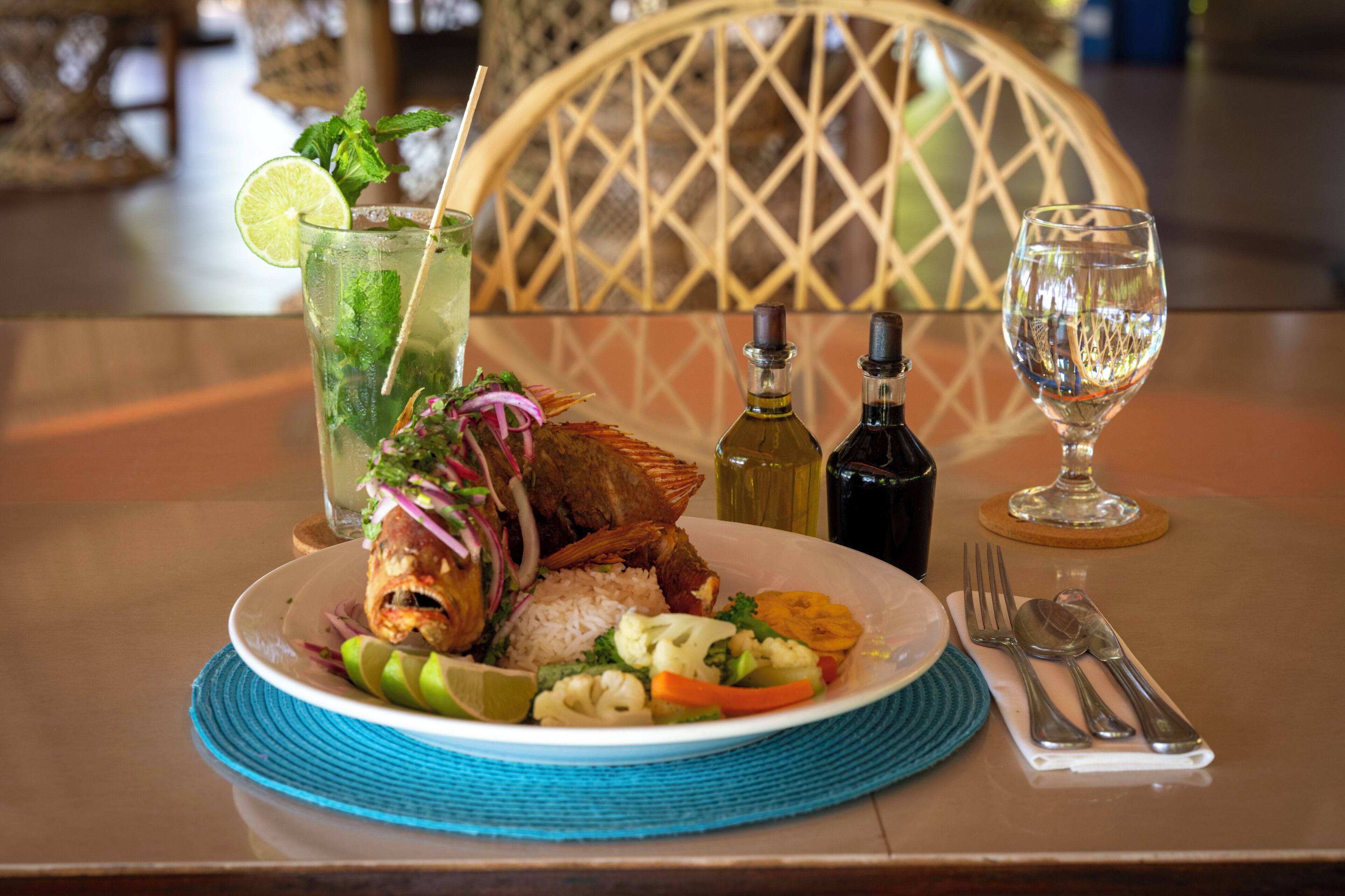 Una mesa con un plato de comida, un vaso de agua y una botella de aceite de oliva.