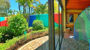 Un jardín tropical con un sendero de piedra que lleva a un baño con un muro de mosaicos.