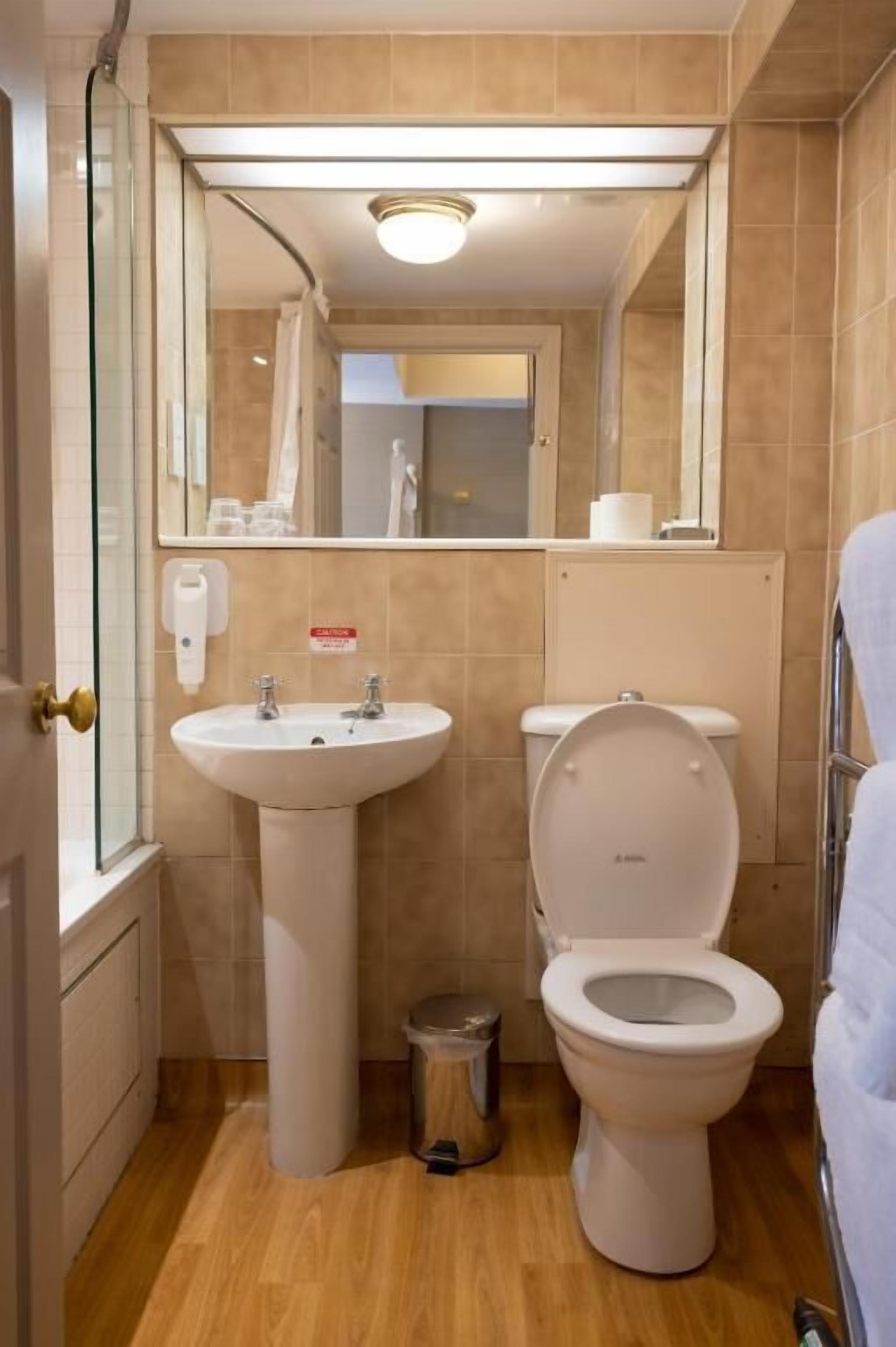 A bathroom with a sink, toilet, and mirror.