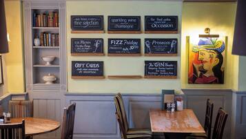 Un interior de restaurante con una pared mostrando distintos platos y una pintura.