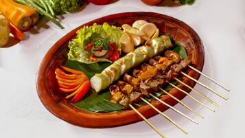 A plate of skewers with vegetables and meat, garnished with lettuce and sliced vegetables.