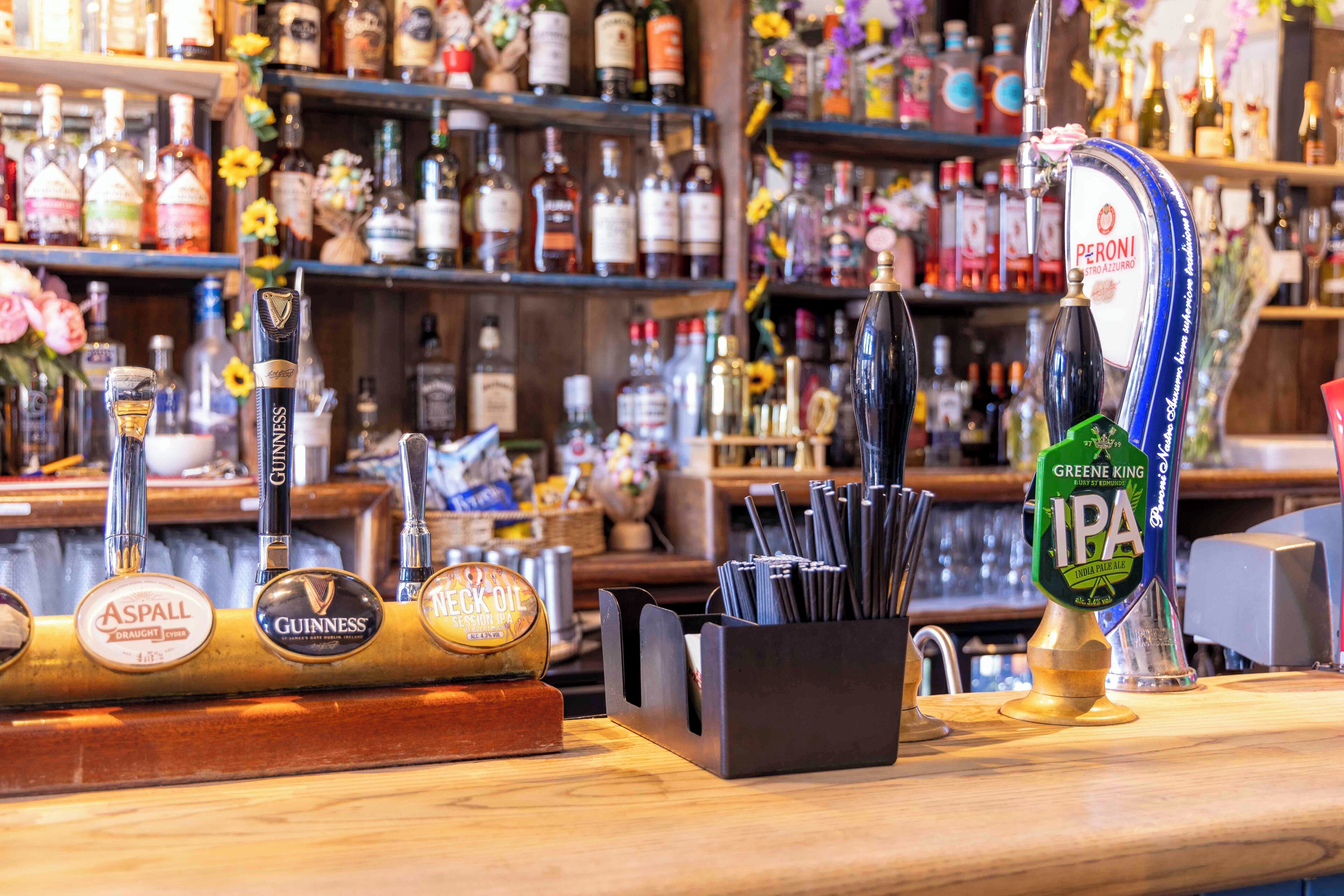 Un bar con múltiples grifos de cerveza, incluyendo marcas como Guinness y Peroni.